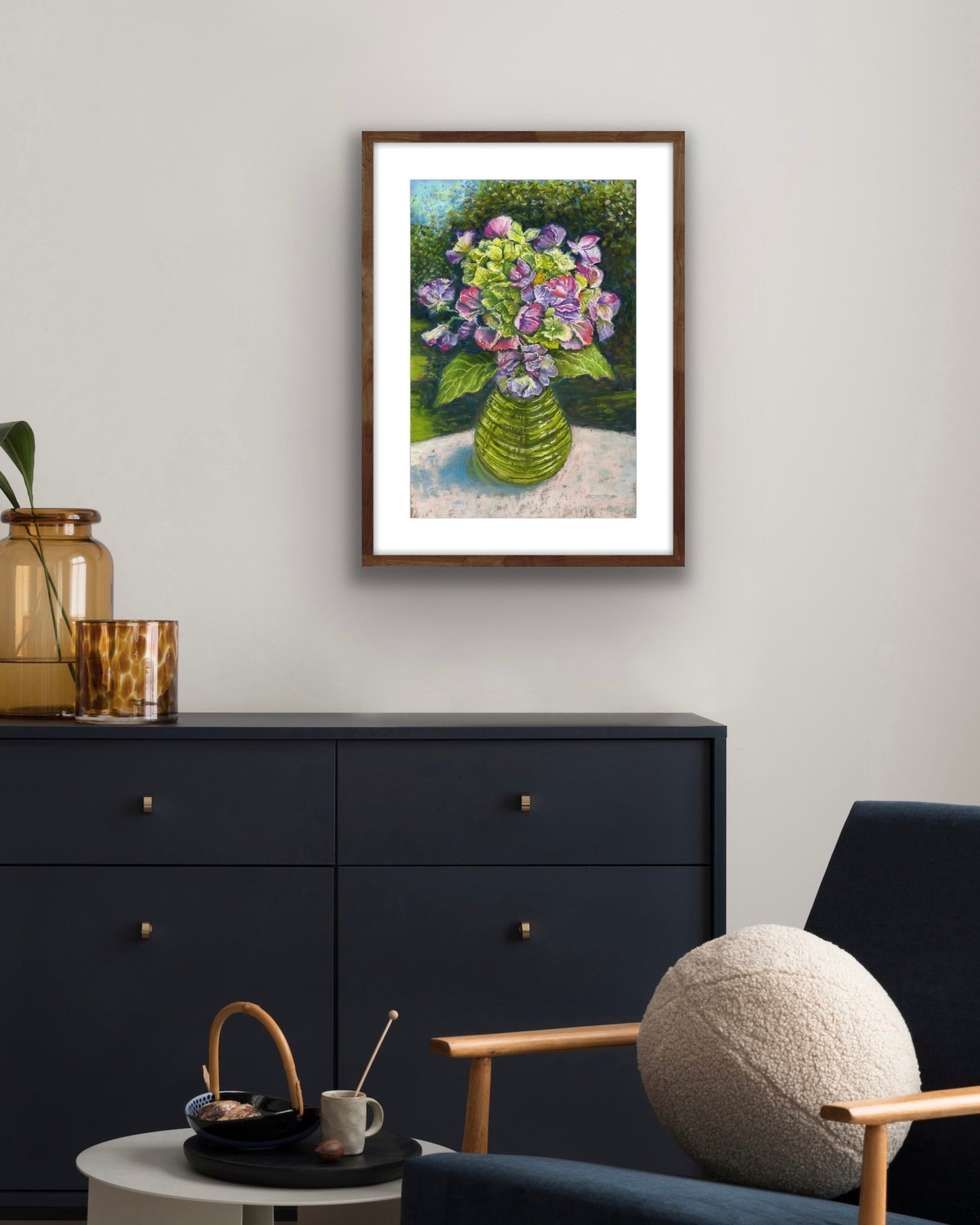 Sweetpeas and hydrangeas in a glass jar on a table cloth with dappled sunlight and trees and garden behind