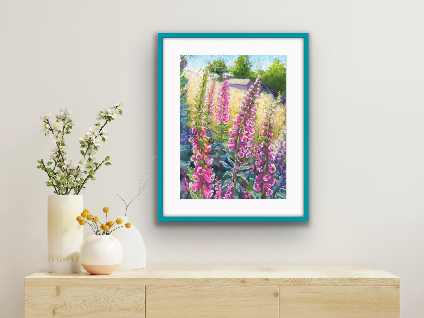 Pink foxgloves in the foreground with a field and building in the background landscape