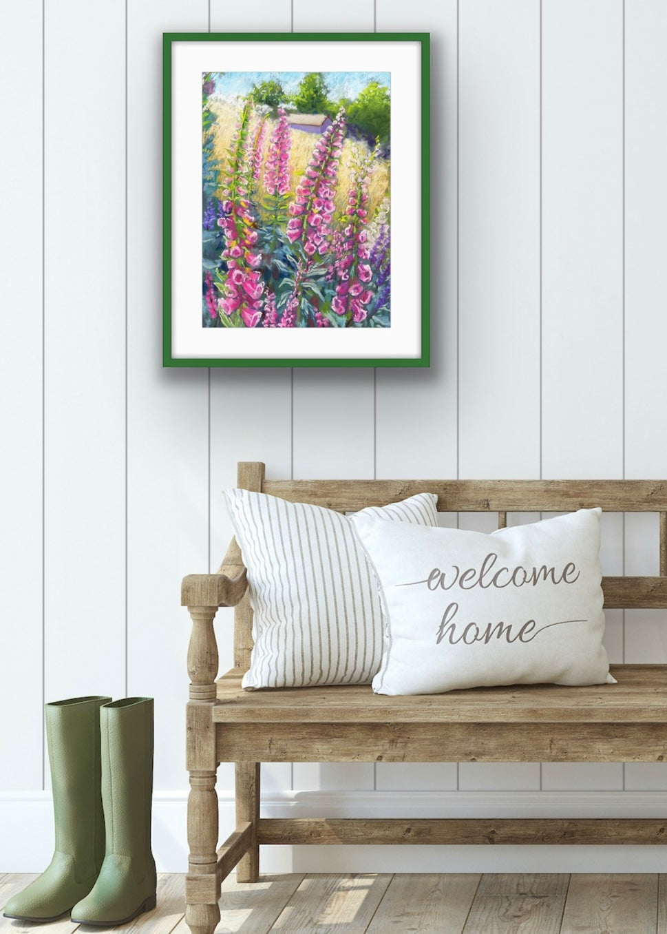 Pink foxgloves in the foreground with a field and building in the background landscape