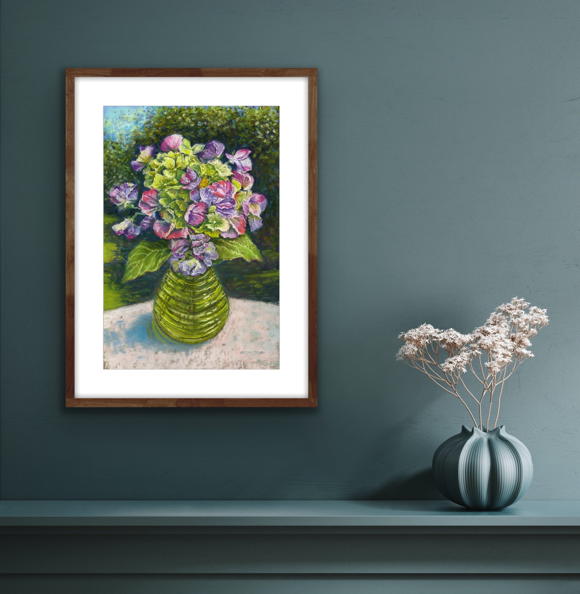 Sweetpeas and hydrangeas in a glass jar on a table cloth with dappled sunlight and trees and garden behind