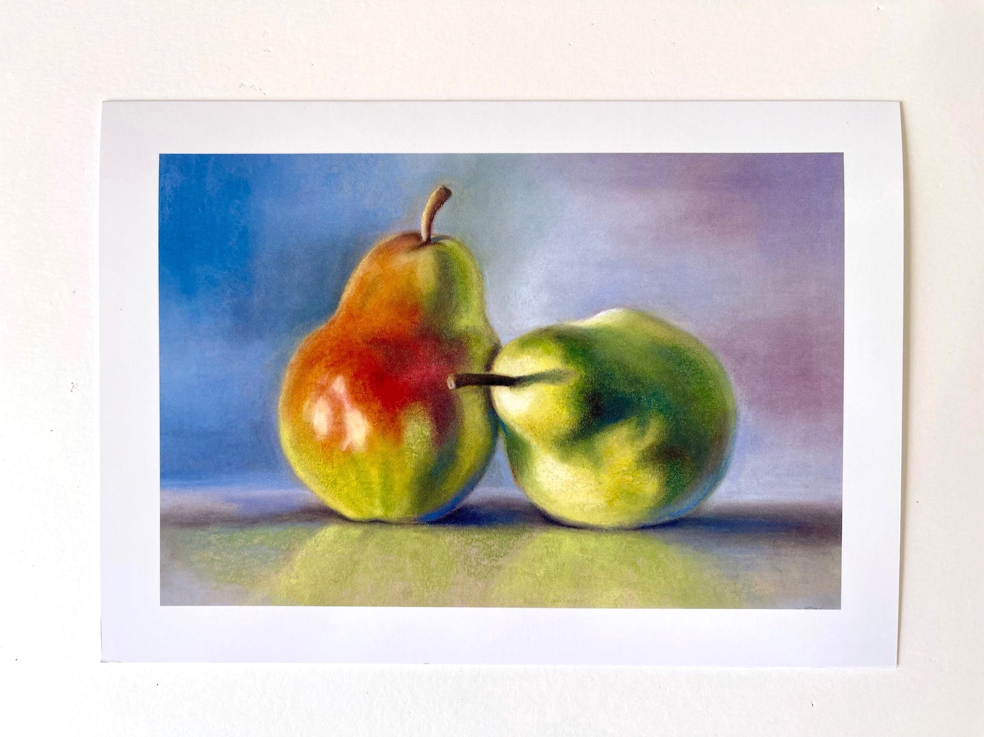 Two vibrantly colourful pears boldly lit with strong shadows, sitting on a polished surface with a reflection of them visible. The pears are bright reds and greens, the background is muted blues and purples. A pastel painting in a traditional style.